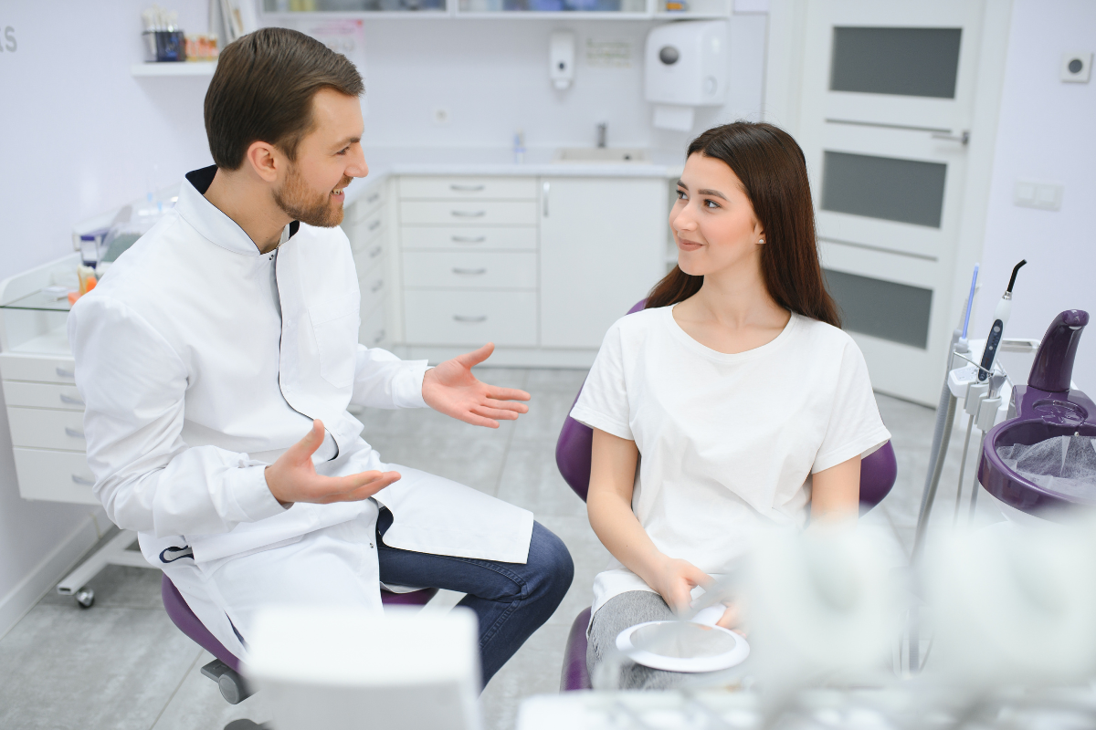 Male dentist discussing treatment options with female patient in modern dental office.
